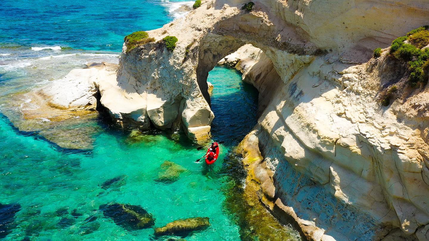 Kayakers below a natural rock arch
